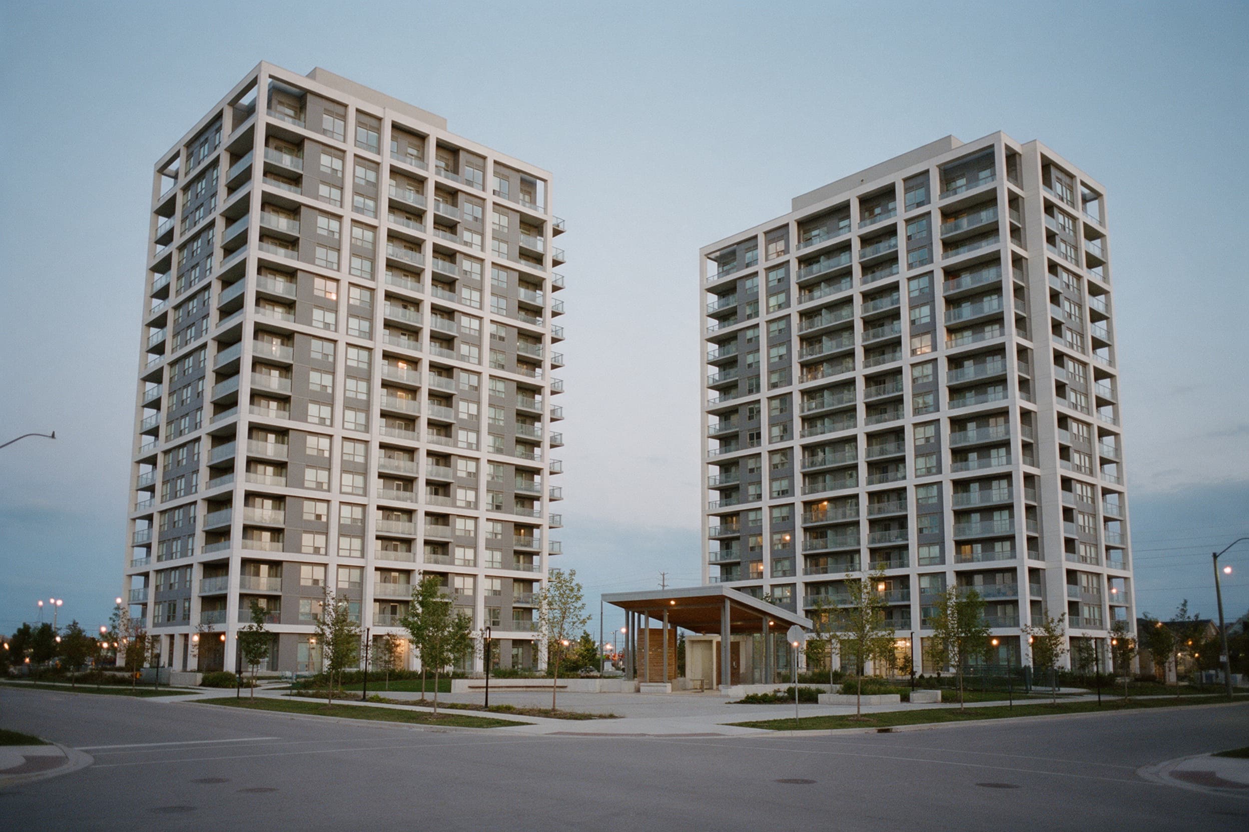 Two twelve-storey condominium towers beside a village square at blue hour