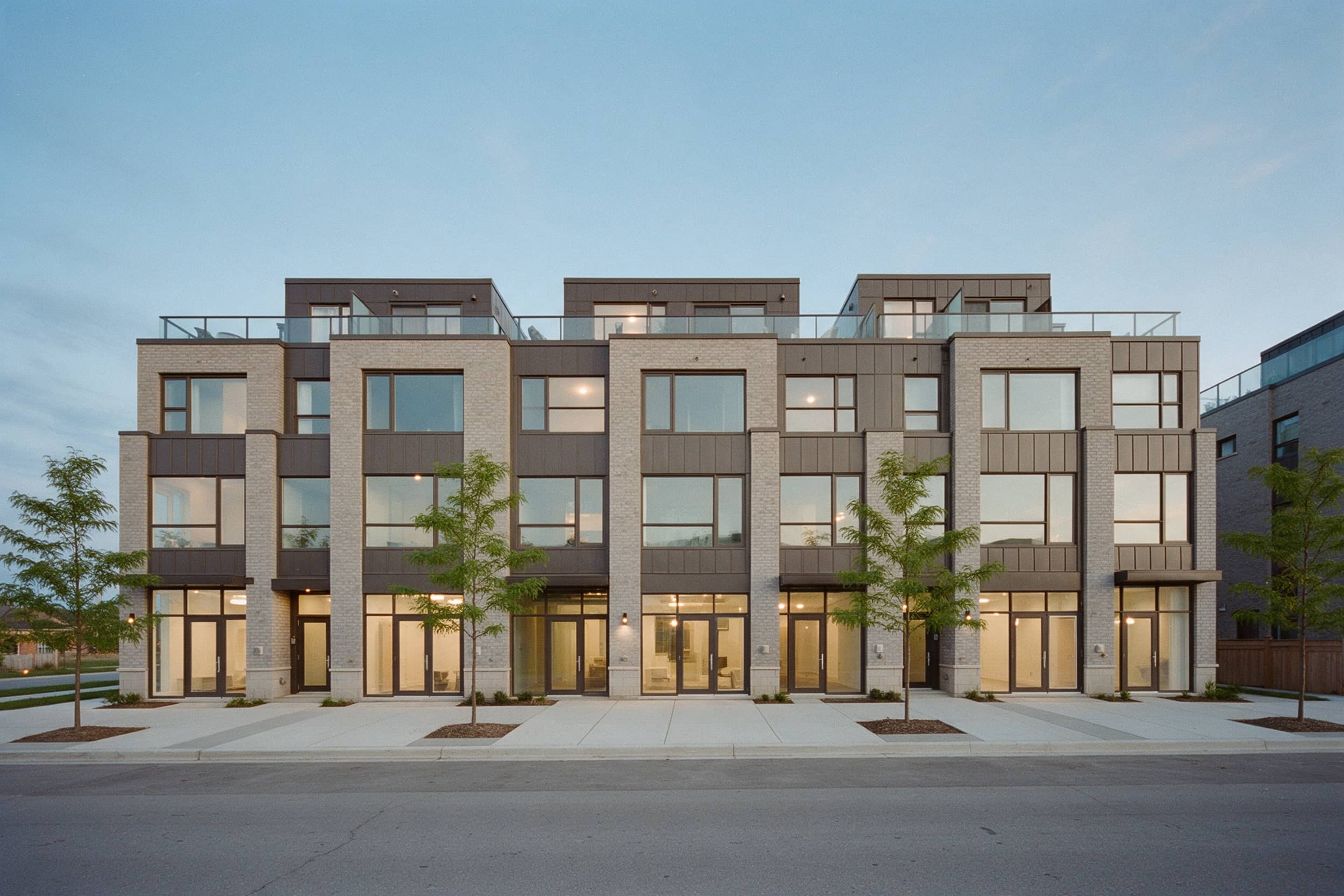 Three-storey urban townhomes with live/work storefronts at dusk